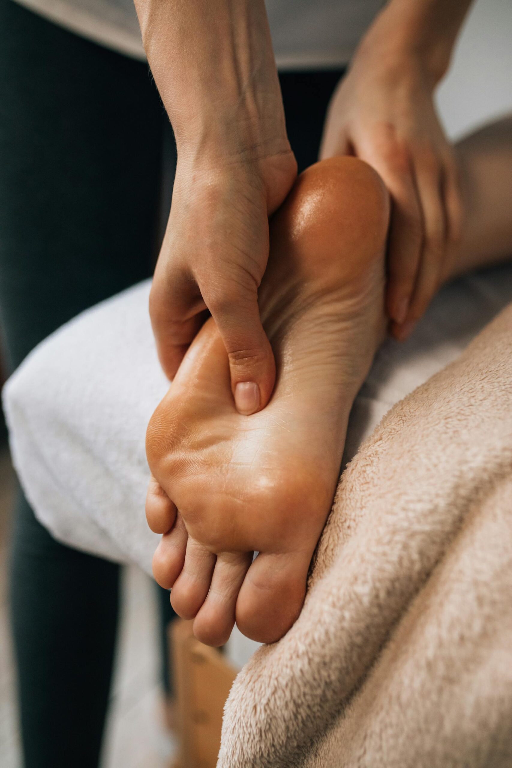 A patient receiving a therapeutic foot massage while lying on a bed, provided by a professional podiatrist.