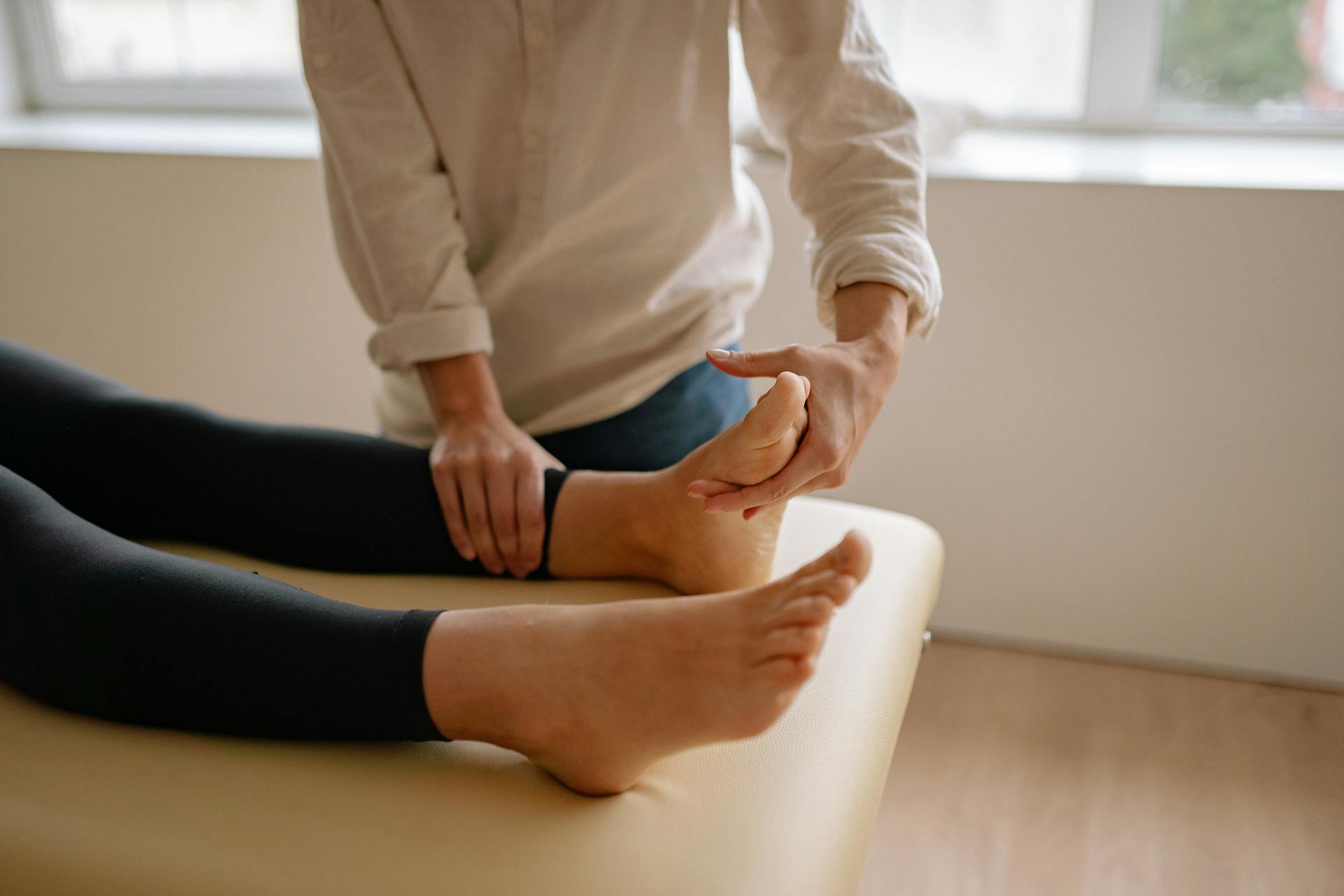 A professional podiatrist massaging a patient's foot to relieve pain and improve mobility.
